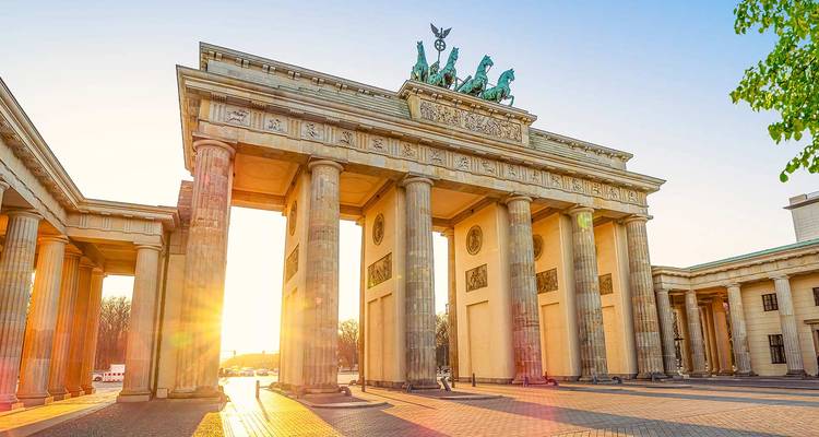 The Brandenburg Gate in Berlin at sunrise with sun flares.