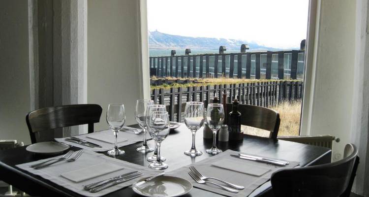 A dining table set up by a window with a scenic view in Puerto Natales.
