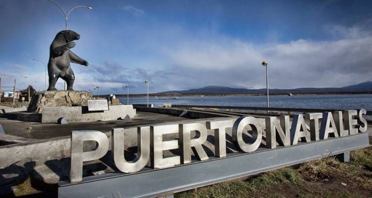 Puerto Natales sign with a bear sculpture beside the water.