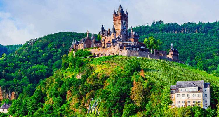 Château sur une colline verdoyante surplombant une vallée.