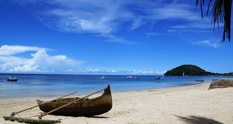 Beach scene with a traditional wooden boat on the sand.