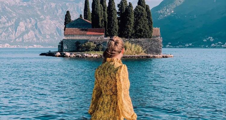 Personne en robe jaune regardant une petite île avec des arbres.
