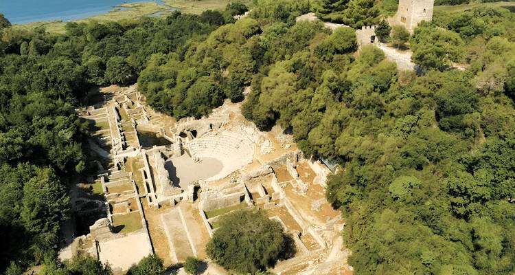 Vue aérienne de ruines antiques entourées d'une forêt dense.