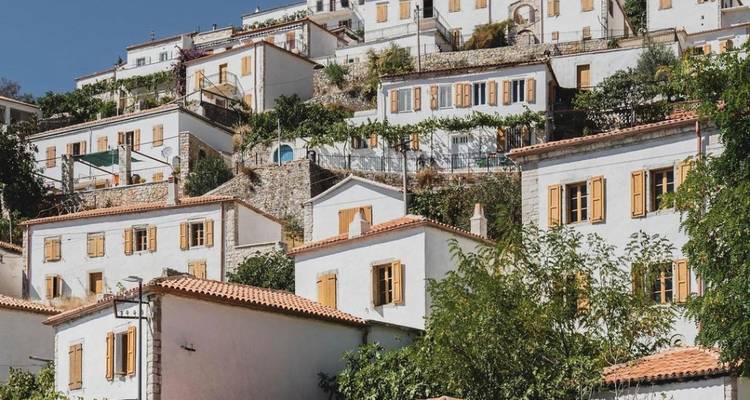 Coteau ensoleillé avec des maisons blanches aux toits et volets orange.
