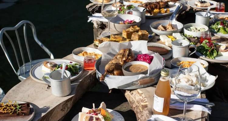 Cadre de restauration en plein air avec divers plats de nourriture sur des tables rustiques.