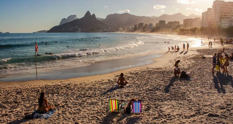 Plage avec des gens et coucher de soleil sur l'océan.