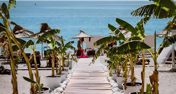 Un chemin en bois menant à une plage avec des parasols et des baigneurs de soleil.