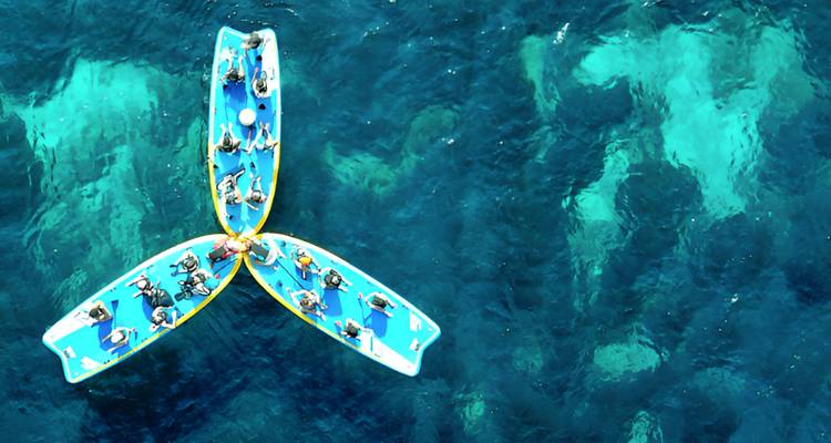 Des bateaux rassemblés en formation sur l'eau vus d'en haut.