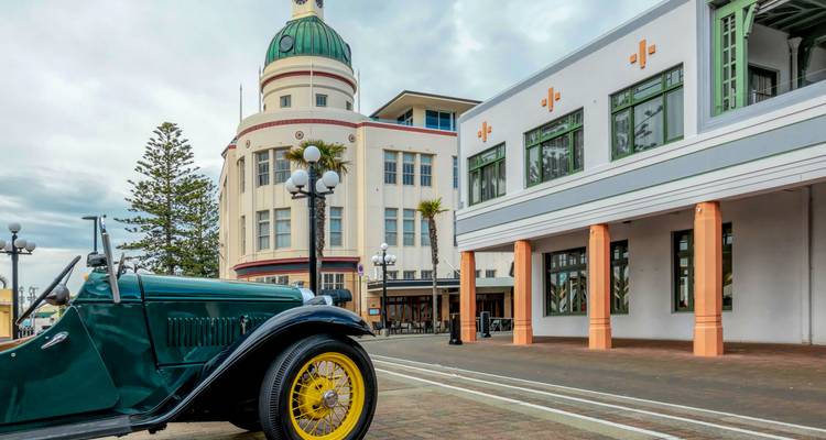 Vintage groene auto geparkeerd voor opvallende Art Deco-gebouwen in een kustplaatsje