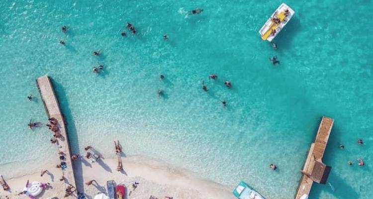 Vue aérienne d'une plage avec des personnes qui nagent dans une eau claire.
