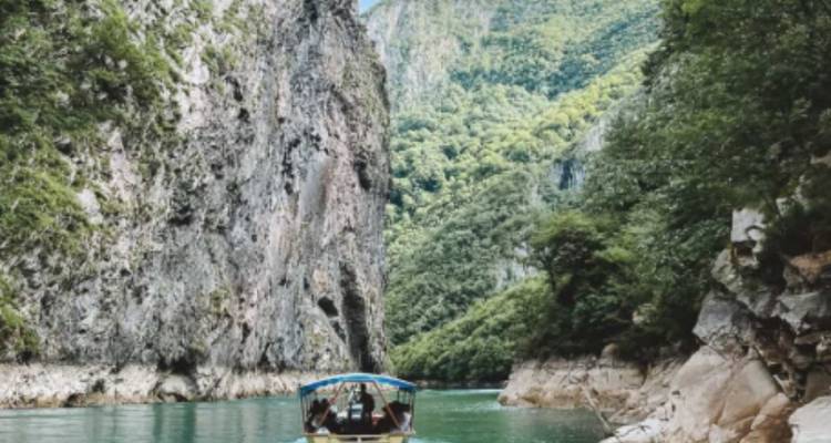 Navigation en bateau dans un canyon de rivière étroit avec des falaises abruptes.