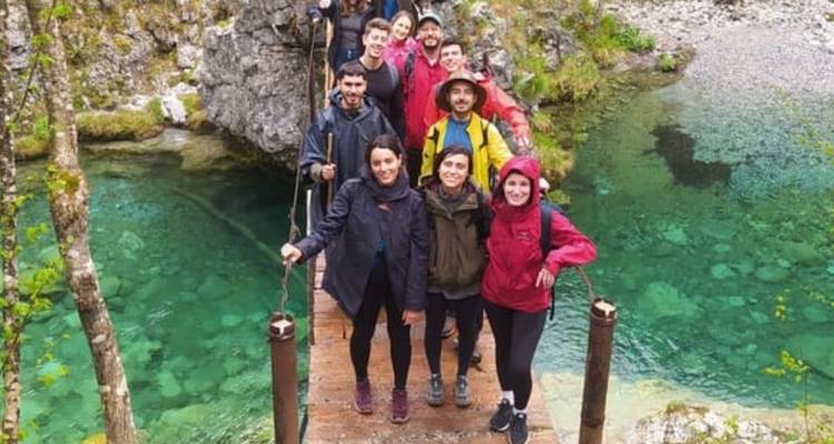 Groupe de personnes debout sur un pont au-dessus d'une eau claire.
