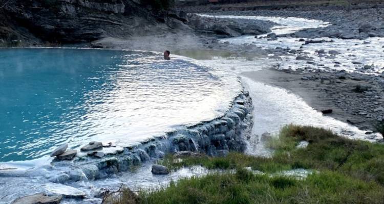 Piscines thermales avec une personne nageant au milieu d'un environnement naturel.