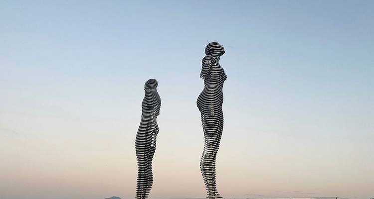 Two abstract sculpture figures against a clear sky.