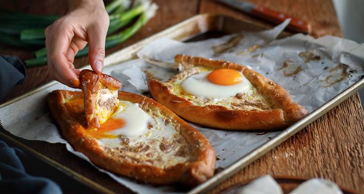 Traditional Georgian dish khachapuri with egg on a baking tray.