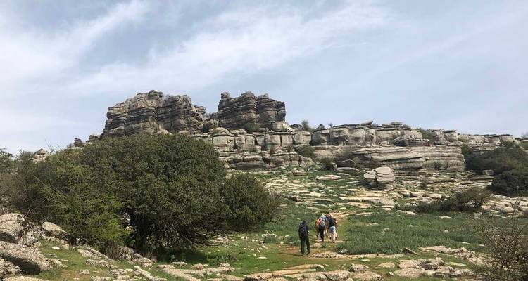 Excursionistas acercándose a las formaciones rocosas de caliza estratificada de la reserva natural de El Torcal