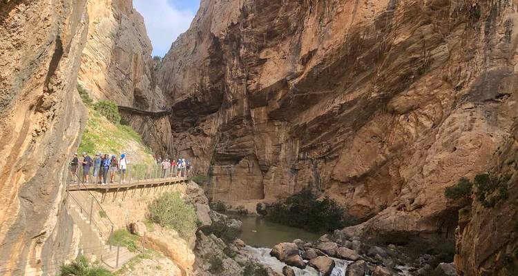 Visitantes caminando por la estrecha pasarela de madera del Caminito del Rey a través de un desfiladero empinado