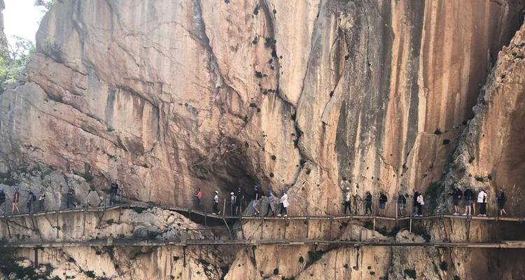 Larga fila de visitantes atravesando una pasarela suspendida que se aferra a las paredes verticales del cañón