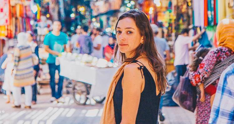 Jonge vrouw staand op een drukke markt.