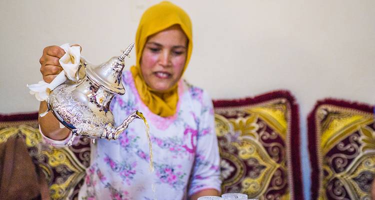 Vrouw die traditionele thee met precisie schenkt.