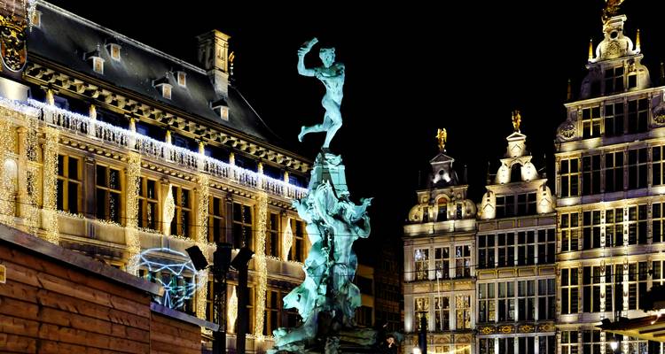 Statue devant des bâtiments historiques la nuit.