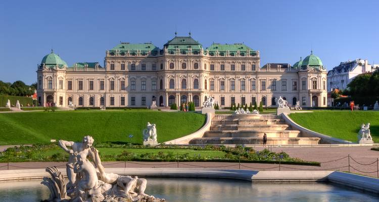 Palais baroque avec un jardin entretenu et une fontaine.
