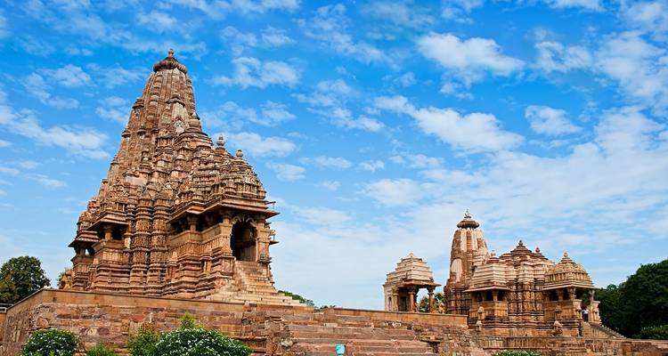 Sunlit ancient temples intricately carved against a bright blue sky.