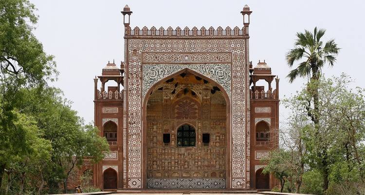 Ornate gate with intricate carvings surrounded by trees.
