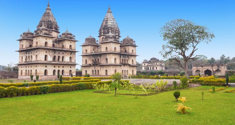 Symmetrical historical tombs in lush green surroundings.