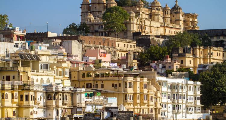 Cluster of traditional Indian buildings with a palace in the background.