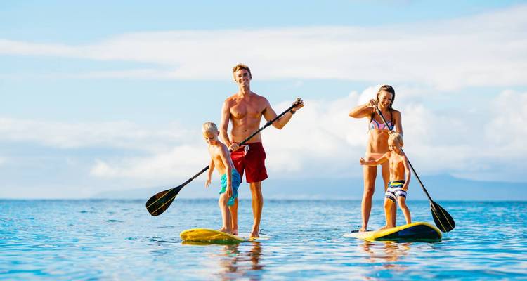Familia haciendo paddleboard en agua azul cristalina.