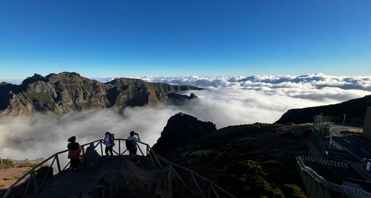 Des gens profitant d'un point de vue en montagne au-dessus des nuages.