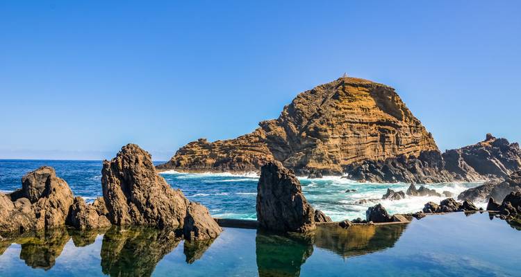 Rocky coastline with natural swimming pools and ocean waves.