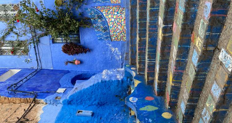 Ruelle urbaine bleu vif avec des marches peintes.