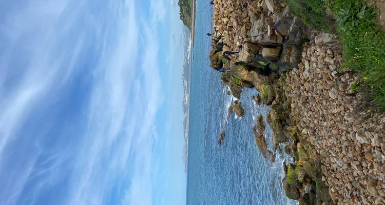Côte rocheuse avec des vagues et un ciel bleu.