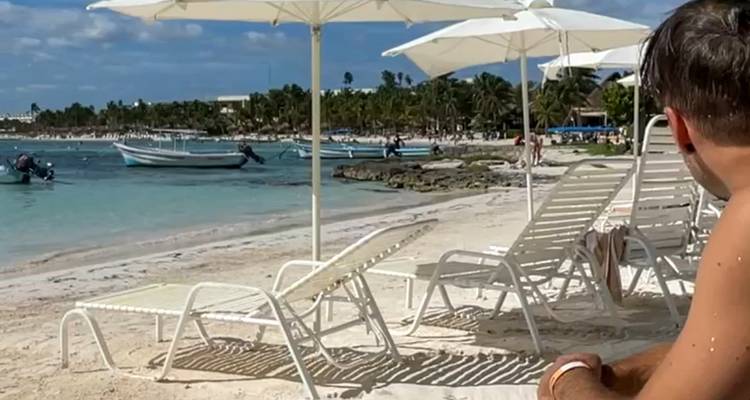 Personne se détendant sur une plage avec des chaises longues et des parasols.