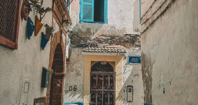 Rue étroite avec bâtiments traditionnels et accents bleus.