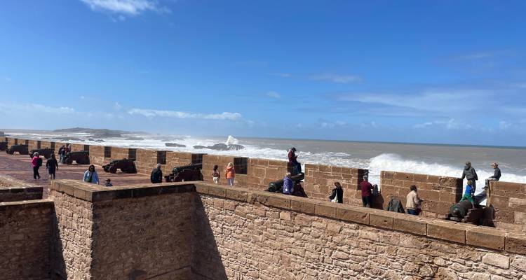 Touristes explorant un fort en bord de mer avec des canons.