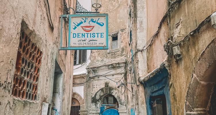 Enseigne de dentiste sur une vieille rue parmi des bâtiments historiques.