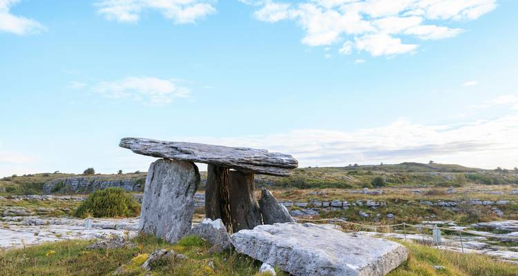 Un dolmen dans un paysage herbeux avec un ciel bleu.