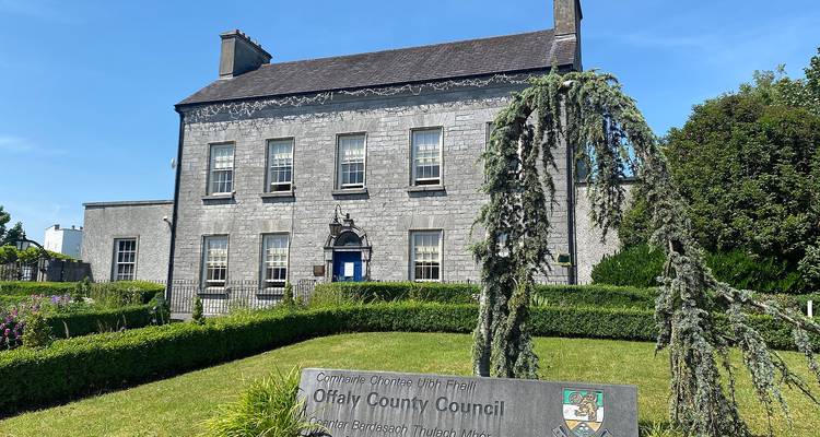Bâtiment en pierre classique avec des portes bleues et un panneau du conseil à l'extérieur.