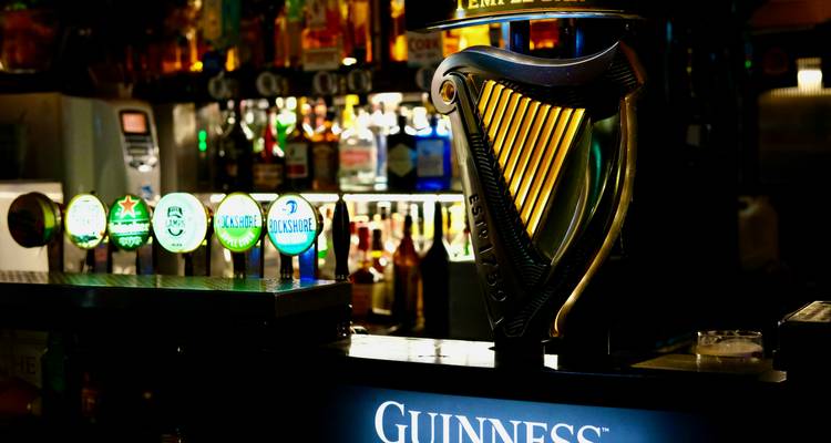 Un comptoir de bar avec diverses boissons, y compris de la Guinness.