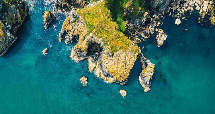 Vue aérienne d'une côte rocheuse et d'une mer bleue.