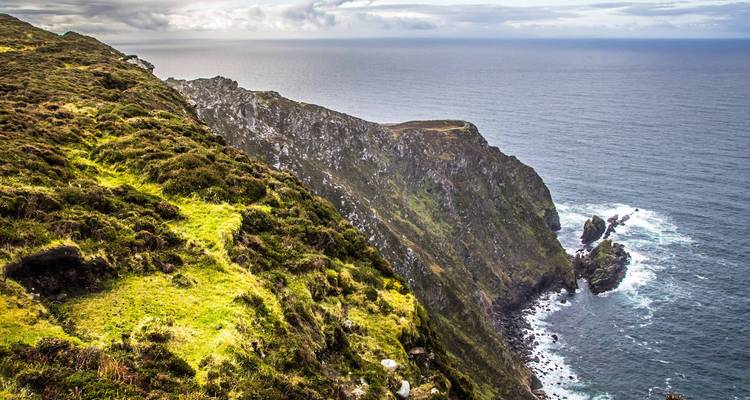 Falaises escarpées surplombant l'océan avec une herbe d'un vert éclatant.