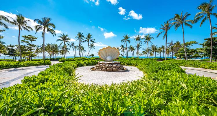 Sculpture of a giant seashell in a park surrounded by trees.