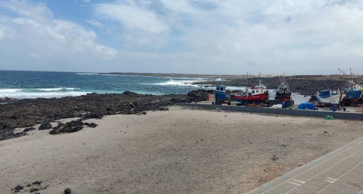Une plage de sable avec des bateaux de pêche et un littoral rocheux.