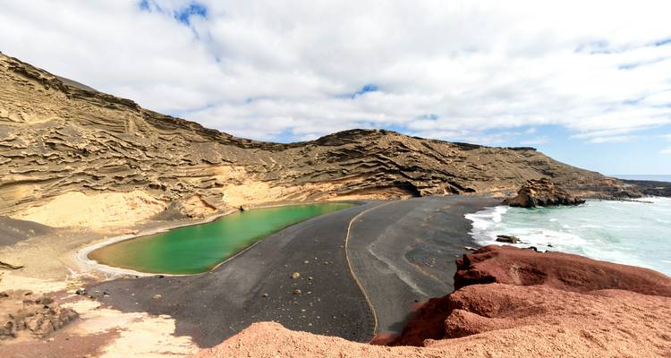 Un lac vert dans un cratère volcanique entouré de falaises.