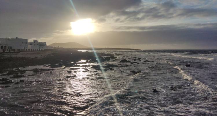 Un littoral rocheux au coucher du soleil avec des vagues qui se brisent et un éclairage dramatique.
