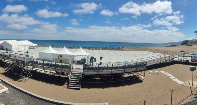 Une installation d'événement au bord de la plage sur une plage de sable avec un ciel bleu.