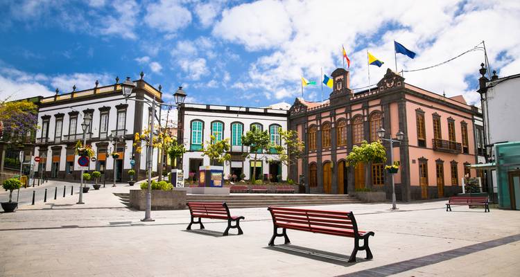 A colorful town square with historical buildings and benches.
